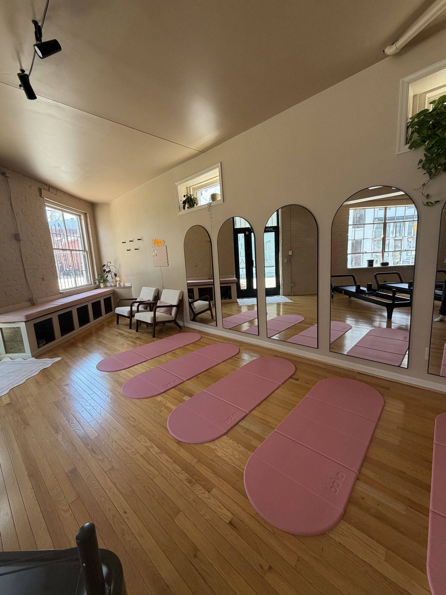 Pink Pilates mats arranged in a row facing the studio's arched mirrors